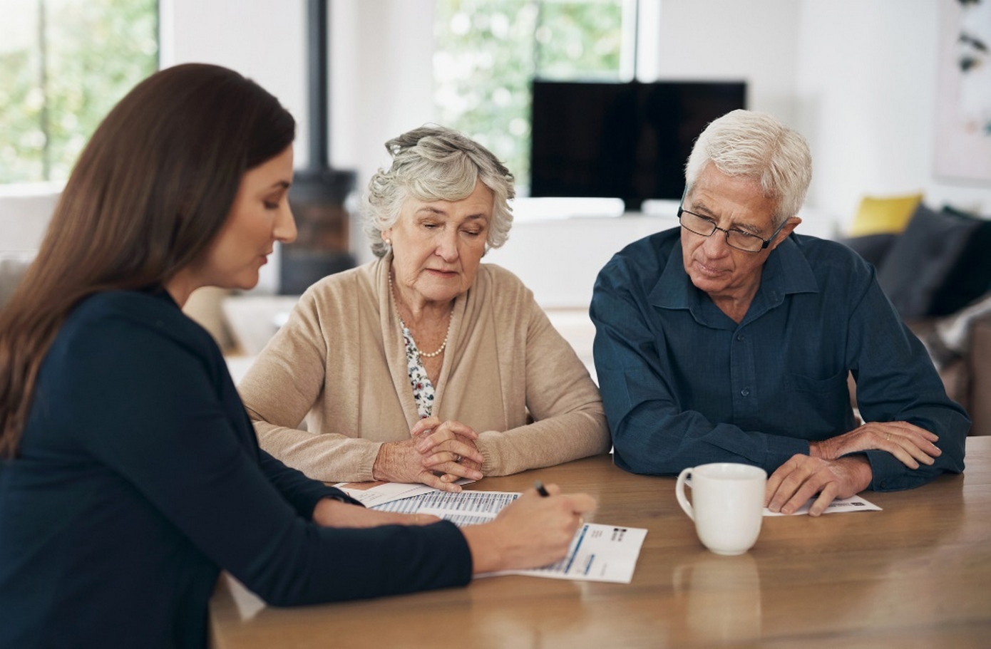 Broker discussing documents with an elderly couple.